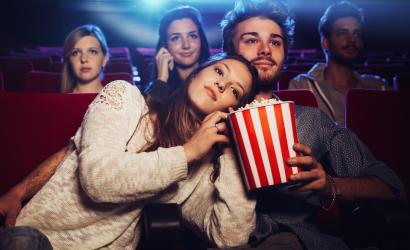 Młoda kochająca para w kinie ogląda film, jedząc popcorn swojego chłopaka