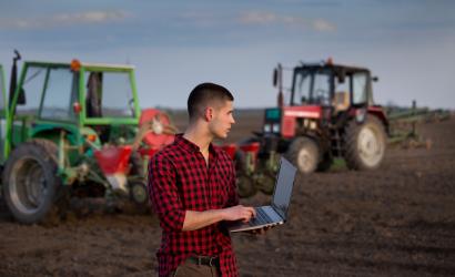 rolnik z laptopem traktory w tle
