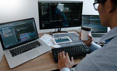 Informatyk siedzacy przed laptopami 