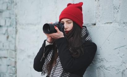 Młoda dziewczyna w czerwonej czapce z aparatem fotograficznym