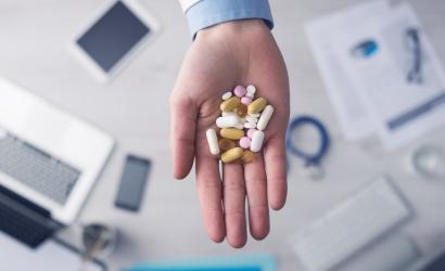 Lekarz daje dużo kolorowych pigułek i tabletek, ręce z bliska z pulpitu w tle, widok z góry