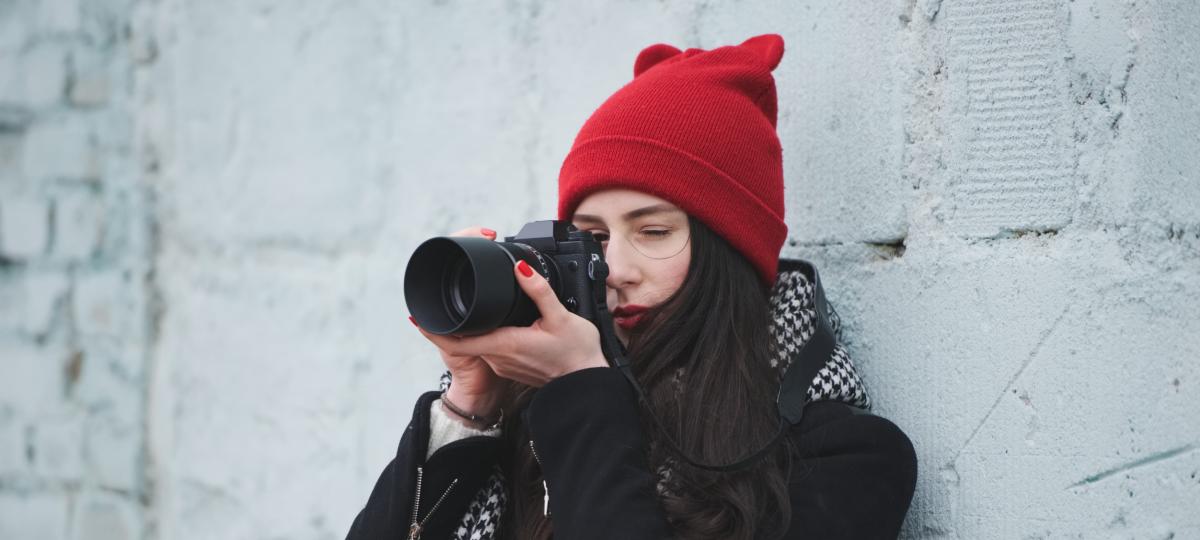 Młoda dziewczyna w czerwonej czapce z aparatem fotograficznym